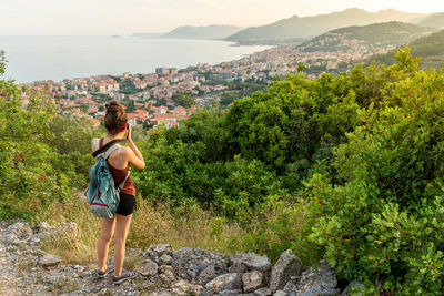 Rear view of woman standing on rock looking at mountain