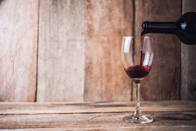 Close-up of wine pouting in wineglass on wooden table