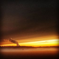 Smoke emitting from factory against sky during sunset