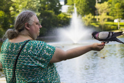 Woman with pigeon by lake