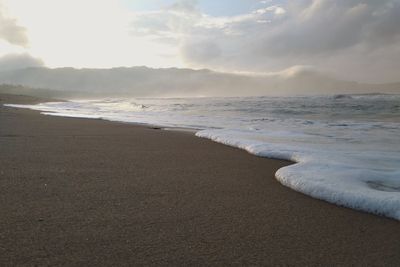 White sea foam on beach and against sky