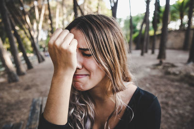 Close-up of young woman crying while sitting outdoors