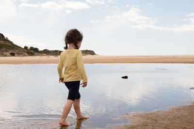 Rear view of girl walking on shore at beach