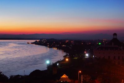 Silhouette of city at waterfront during sunset