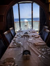 Empty chairs and table by sea against sky