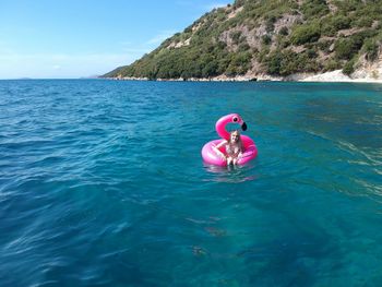 Woman swimming with pink inflatable ring in sea during sunny day