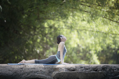 Side view of young woman sitting on tree