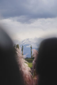 Man with arms outstretched against sky