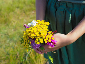 Midsection of woman holding purple flower