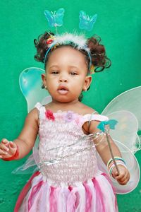 Portrait of cute baby girl wearing fairy costume against wall