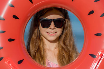 A teenage girl in glasses looks through an inflatable ring. close-up.