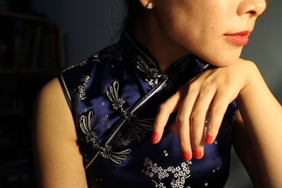 Midsection of young woman in traditional clothing at home