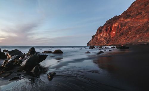 Rocks on sea shore against sky