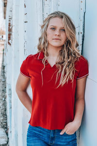 Portrait of a beautiful young woman standing against wall