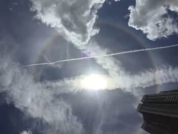 Low angle view of sun shining through clouds