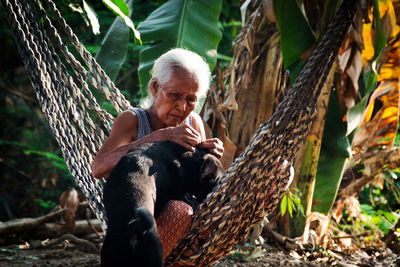 Woman sitting on tree in forest