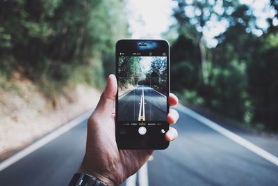 Cropped image of man photographing through smart phone