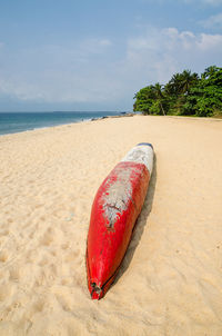 Close-up of dugout canoe on sand at beach against sky