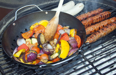 High angle view of vegetables in pan with meat on barbecue