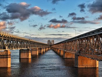 Pier on river against cloudy sky