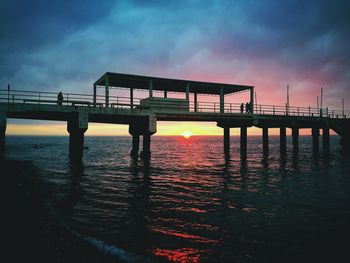 Silhouette of bridge over sea during sunset