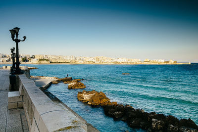 Swimming pool by sea against clear sky