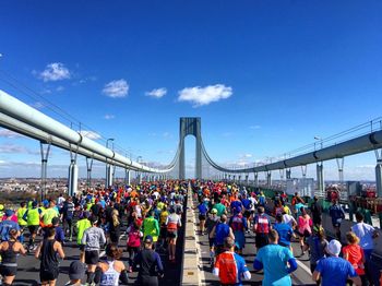 People on bridge in city against sky