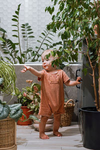 Little funny baby boy helping his mother take care for potted plants in the bathroom 