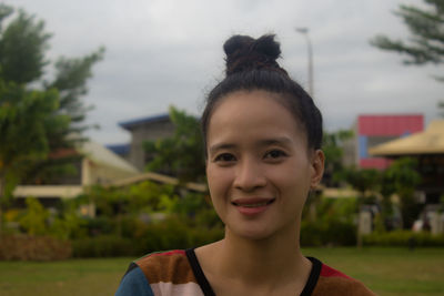 Portrait of young woman standing against trees