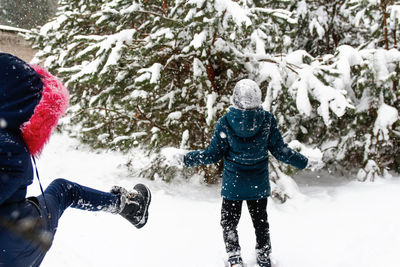 Funny children in winter park playing snowballs, actively spending time outdoors. winter snowy 