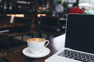 Coffee mug and laptop on wooden table.