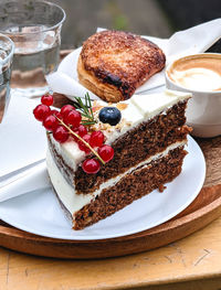 Close-up of carrot cake with fresh fruits dessert in plate on table