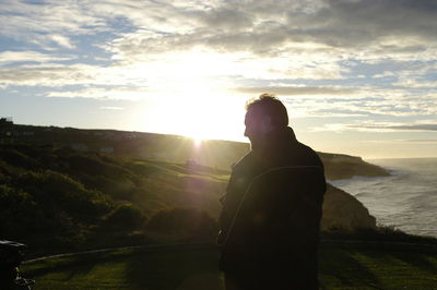 Man standing on rock against sky during sunset