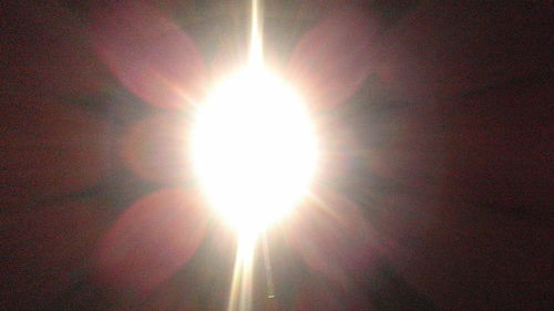 Low angle view of sun shining in sky