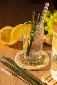 Glass of water with fresh lemon juice with reusable glass straws detox cold tonic water with sunny