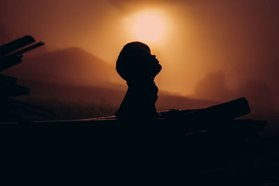 Silhouette boy against orange sky during sunset