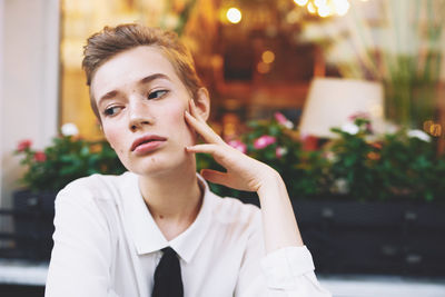 Portrait of young woman standing against trees