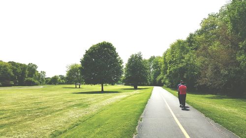 Rear view of man on road against clear sky