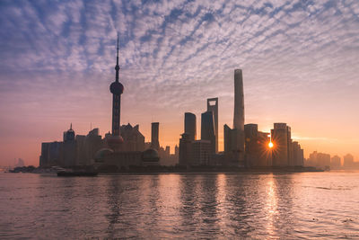 Modern buildings in city against sky during sunset