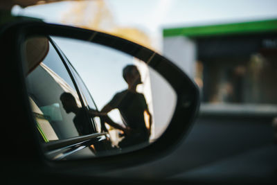 Reflection of man on side-view mirror