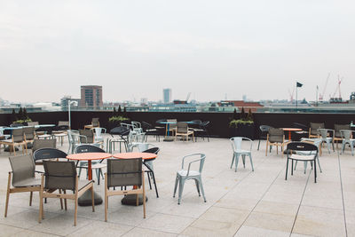 Empty chairs and tables at outdoor cafe in city