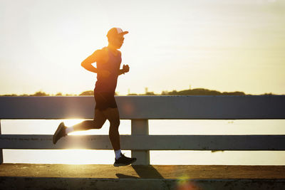 Side view of man running on shore against sky