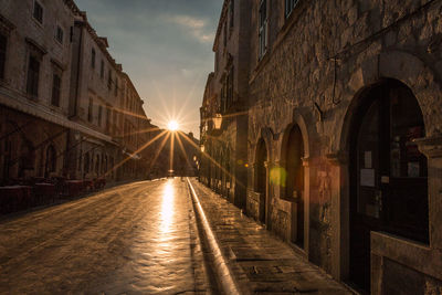 Street amidst buildings against sky during sunset