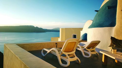 Street journals- lounge chairs and table by sea against sky