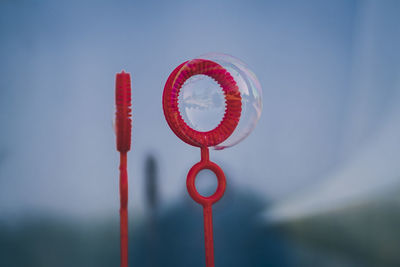 Close-up of red bubble wand against sky