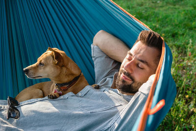 Portrait of attractive european man on hammock with cute sleepy dog.