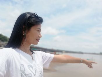 Portrait of smiling young woman standing against sky