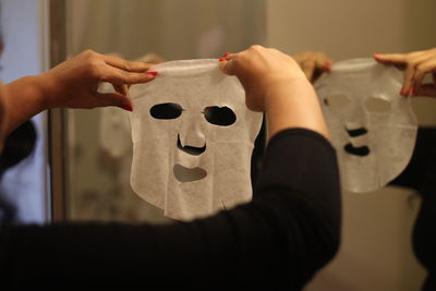 Cropped hands of woman using facial mask at home