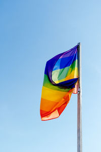 Low angle view of pride flag against clear blue sky