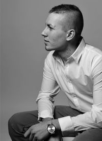 Thoughtful young man sitting against wall